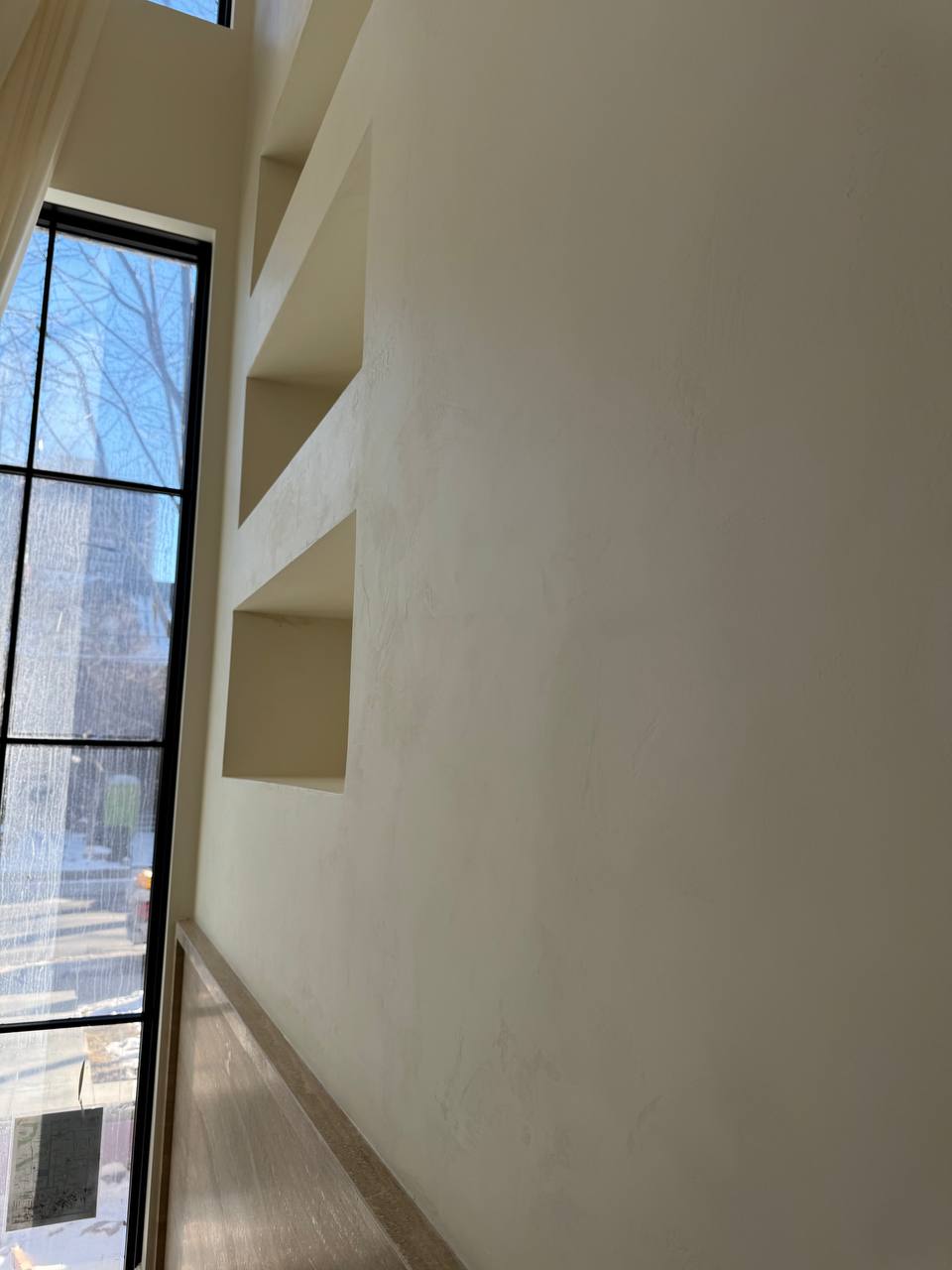 A close-up view of a 20-ft fireplace accent wall finished in Venetian plaster in a luxury home in Rosedale, Toronto, showcasing its subtle texture and depth.