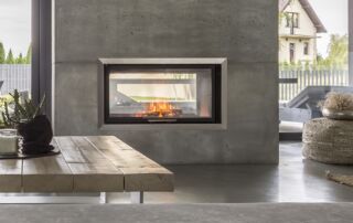 Fireplace wall finished in rough, dark gray microcement, adding a bold and textured look to the living room of a house in North York, Toronto.