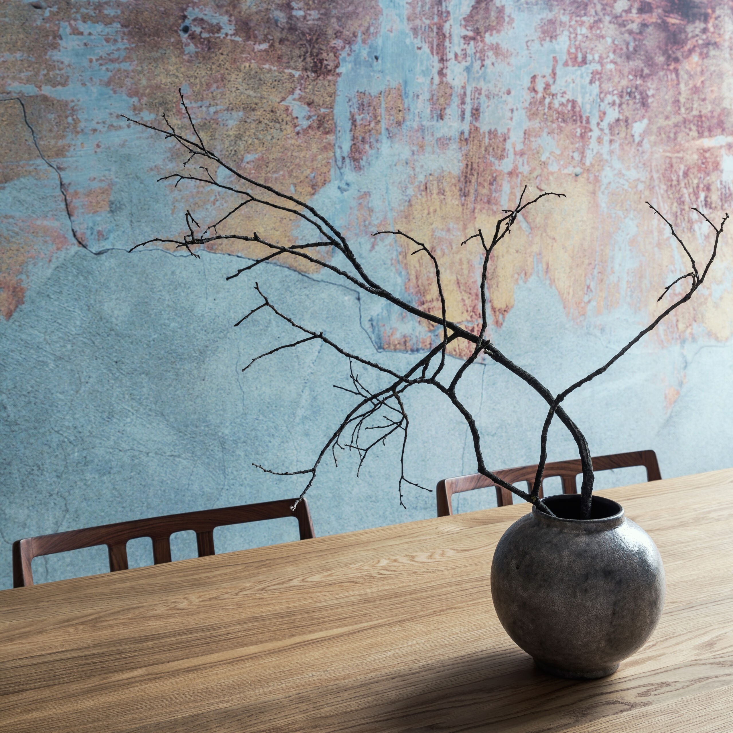 Dining room in a loft apartment with Mediterranean blue limewash paint as the base color and rustic orange-beige Venetian plaster accents, creating a stylish and eclectic design.