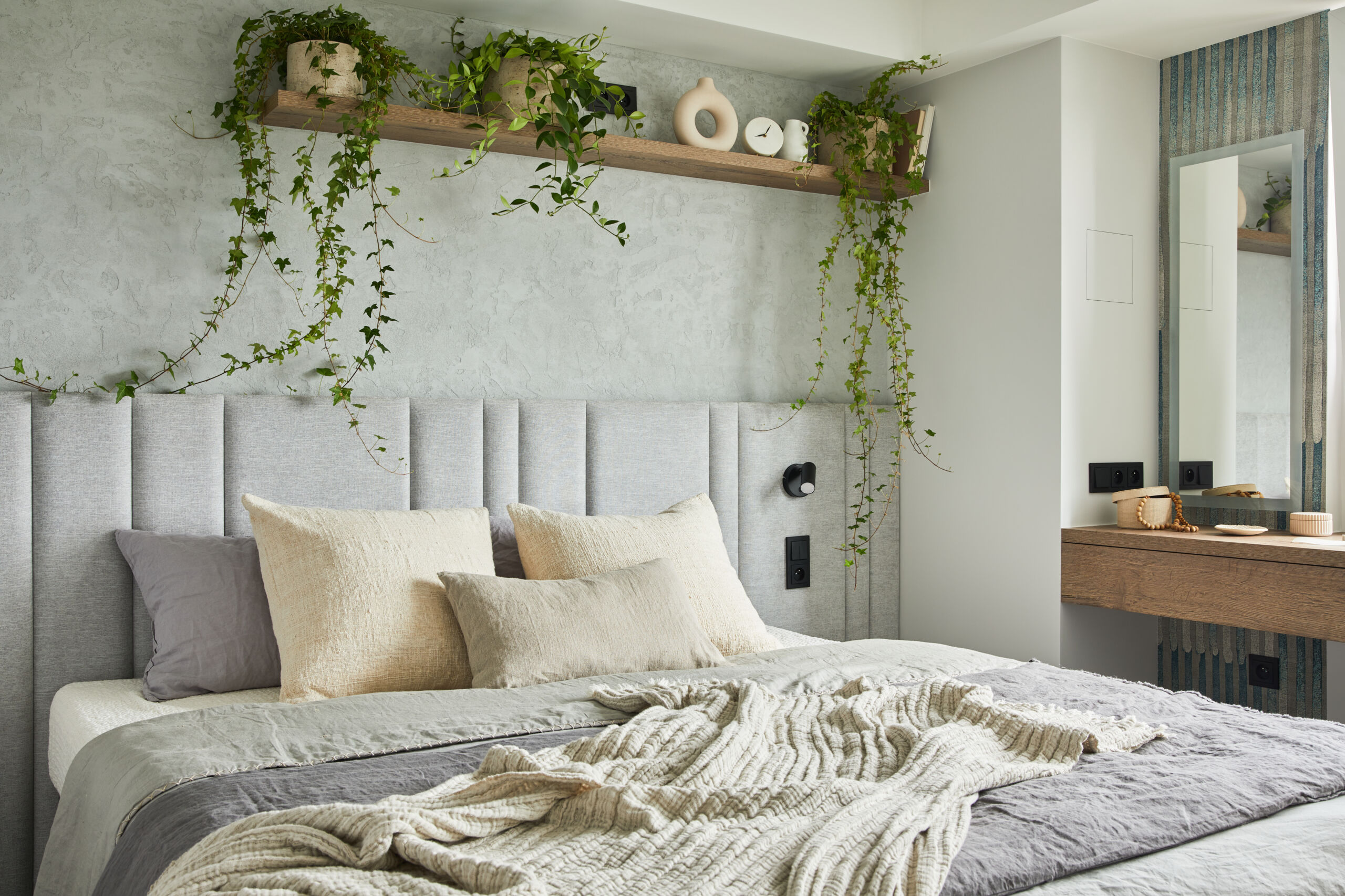 Stylish microcement textured wall in a bedroom interior of a modern apartment in soft green color.