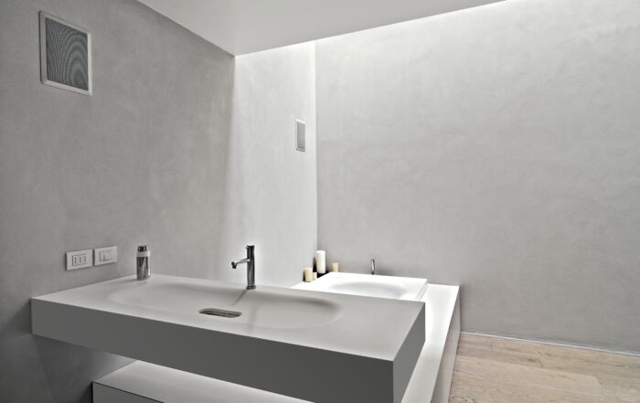 Modern bathroom with shower walls and vanity finished in microcement, giving a concrete-like finish for a sleek, minimalist look.