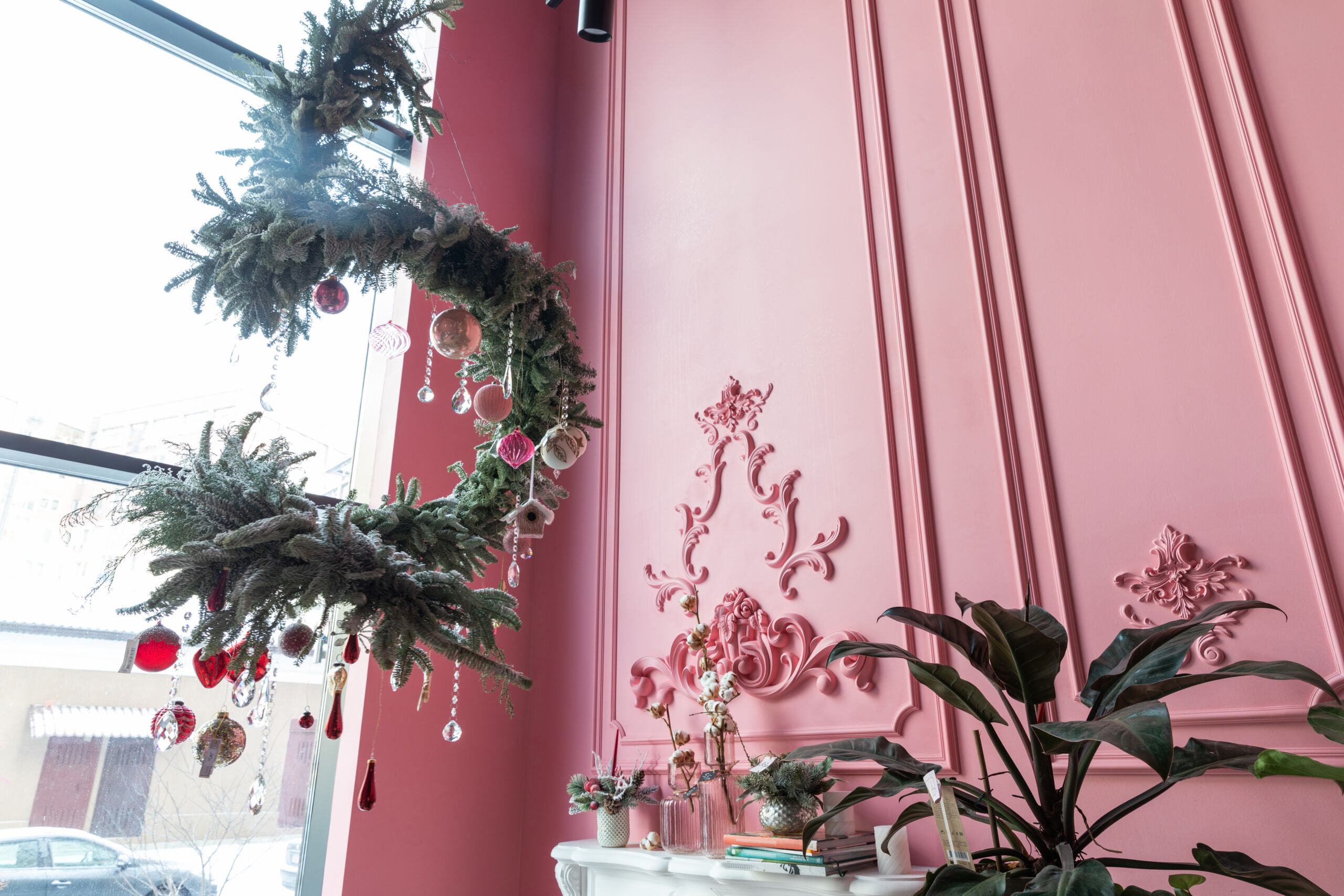 Interior view of a stylish pink-painted room decorated for Christmas with festive holiday decor.