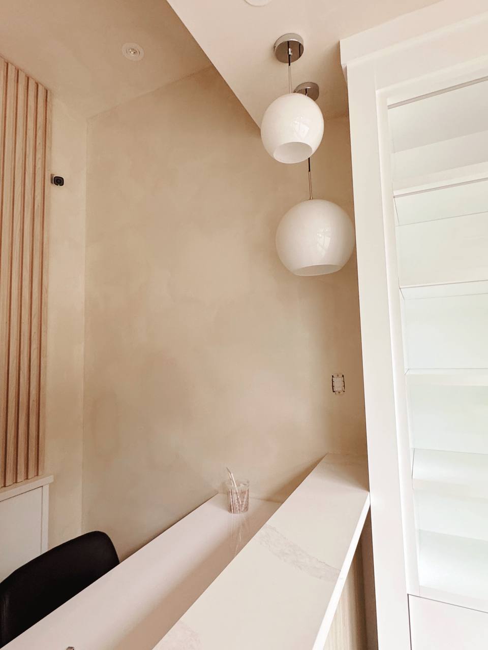 A laser clinic reception area with walls and ceilings finished in limewash, featuring Edgecomb Gray by Benjamin Moore, creating a soft, natural texture that enhances the minimalist, serene aesthetic.